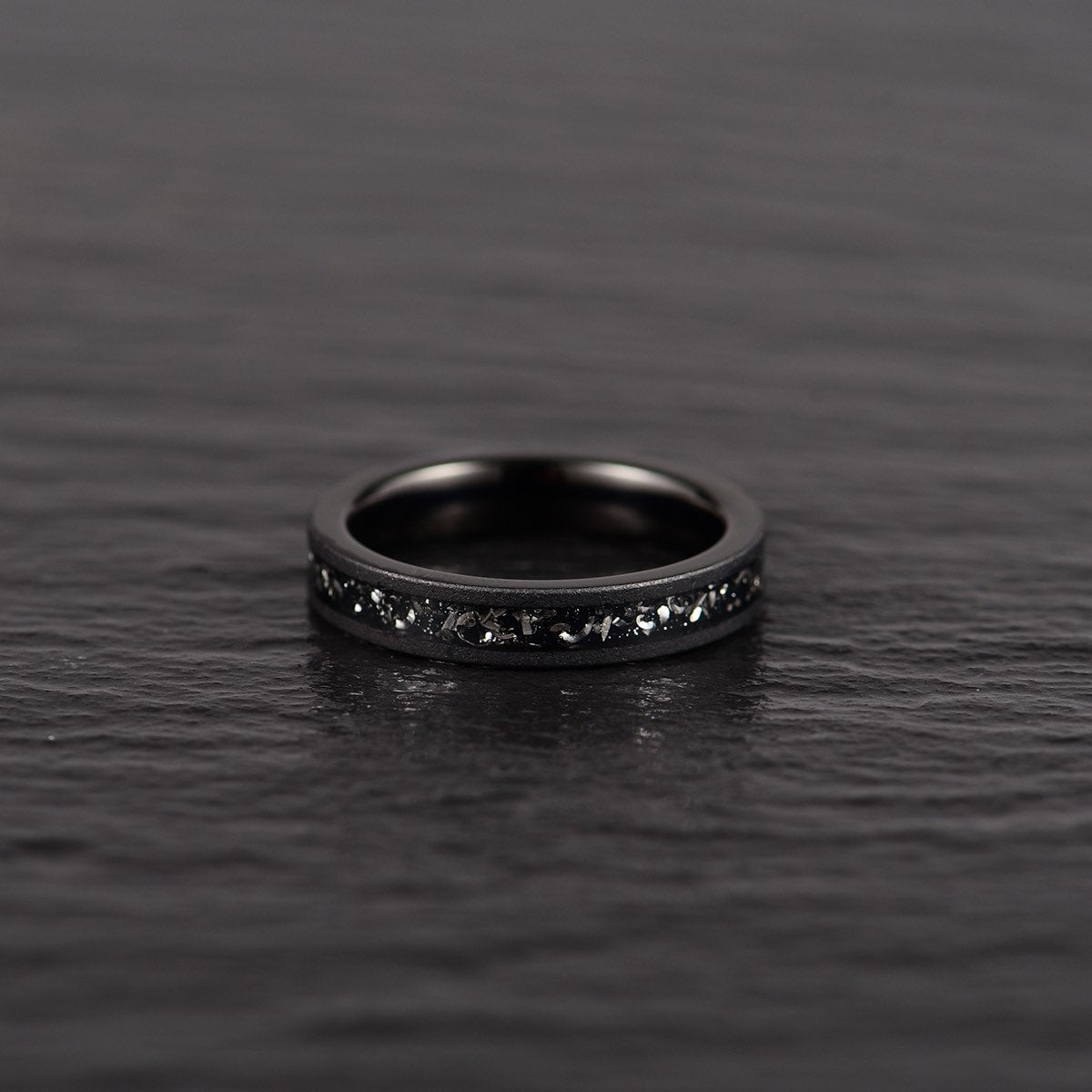 Crushed meteorite inlay sandblasted black tungsten men's wedding band 4mm facing front laid down 